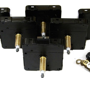 May include: Five black clock movements with gold-coloured shafts and white plastic tips. The movements are arranged in a staggered pattern. A small bag of assorted hardware is in the lower right corner of the image.
