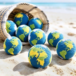 May include: A collection of blue, yellow, and green crocheted globe-shaped balls spilling from a woven basket onto a sandy beach. The balls are detailed with continents and oceans, creating a playful educational theme.
