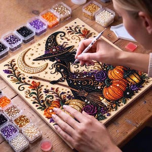 May include: A diamond painting kit featuring a witch silhouette, a crescent moon, pumpkins, and floral elements. The design is composed of colourful resin beads applied to a board, accompanied by small containers of beads and a stylus tool.