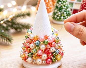 May include: A white foam cone base decorated with a dense arrangement of multicolored, glossy, spherical beads in shades of pink, green, orange, red, blue, and white, secured with small metal pins to create a textured, tree-like ornament.