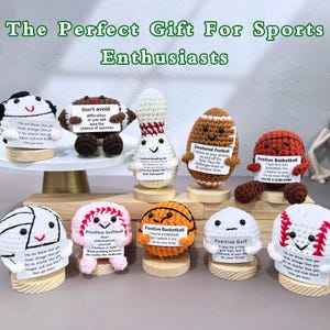 May include: A collection of crocheted sports-themed figurines, including a football, basketball, and baseball, each with a positive message. The text "The Perfect Gift For Sports Enthusiasts" is at the top.