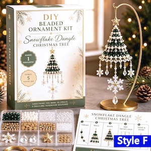 May include: A DIY beaded ornament kit for a snowflake dangle Christmas tree, including a box with text, a clear plastic organizer filled with green, white, gold, and clear beads, a gold display stand, and an instruction sheet labeled Style F.