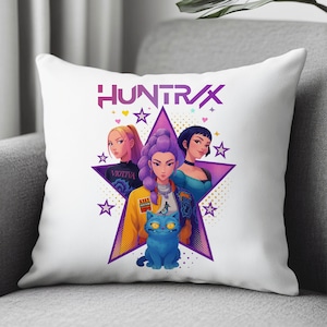 May include: White throw pillow featuring a graphic of three women and a blue cat inside a purple star. The pillow has the word "HUNTRAX" above the star and the word "VIOTIVA" below the star. The design includes stars and hearts.