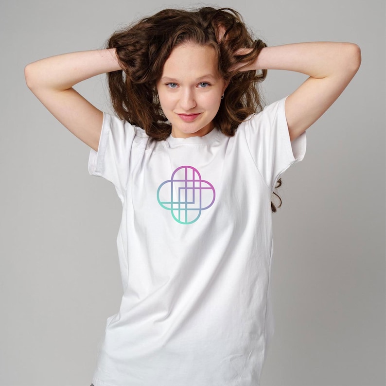 Puede incluir: Una camiseta blanca con un dise&ntilde;o geom&eacute;trico en tonos morados y turquesas. El dise&ntilde;o es una forma estilizada de tr&eacute;bol de cuatro hojas. La camiseta es de material suave y tiene mangas cortas.