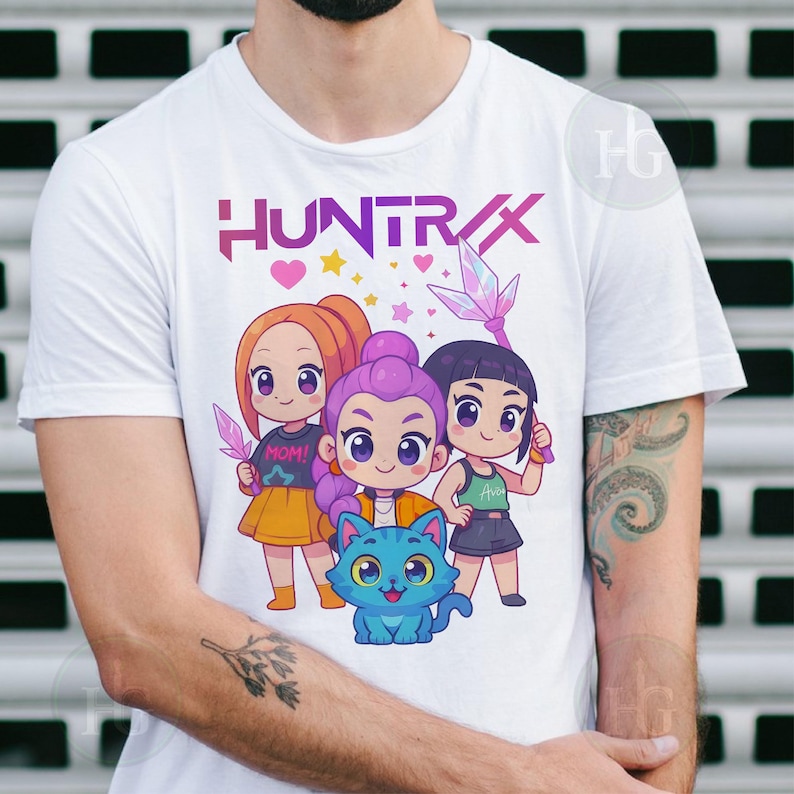 Pu&ograve; includere: T-shirt bianca con la scritta "HUNTRAX" in viola e rosa, e un'illustrazione a cartoni animati di tre ragazze e un gatto blu. Le ragazze tengono in mano dei cristalli e indossano abiti diversi.