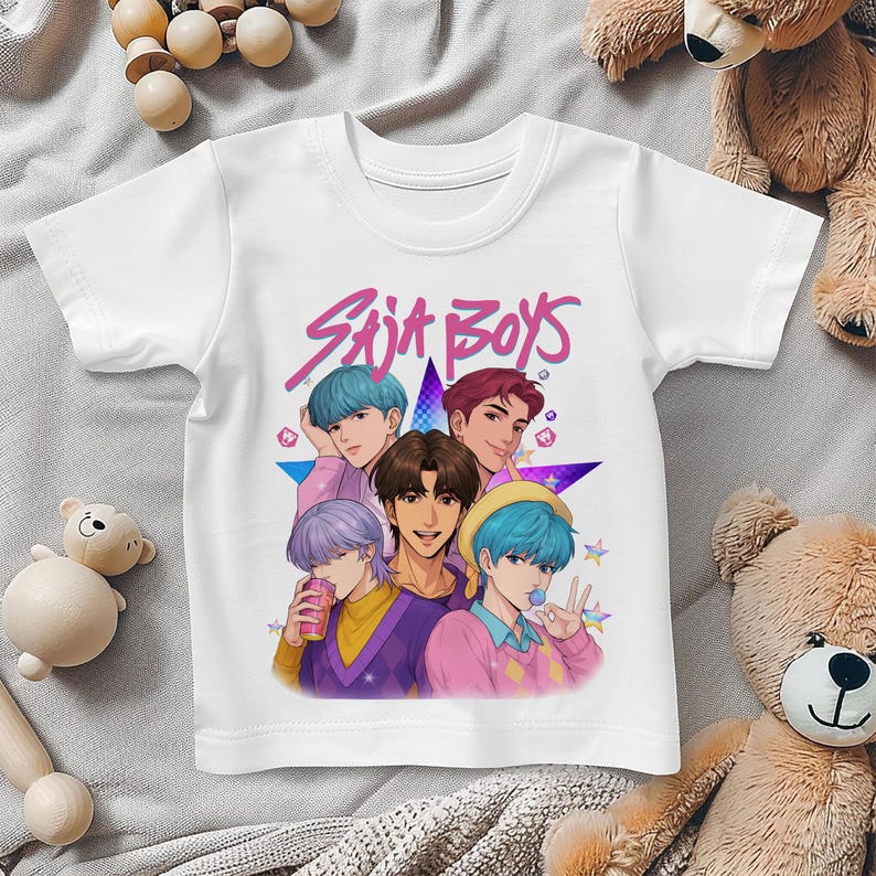 May include: White t-shirt featuring a colorful graphic of five anime-style characters with different hair colors. The text "Saja Boys" is written in pink above the characters. The shirt is made of a soft material.