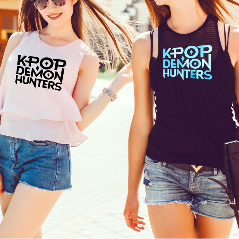 K&ouml;nnte beinhalten: Zwei Frauen tragen &auml;rmellose Oberteile und Jeansshorts. Ein Oberteil ist hellrosa mit dem Text "KPOP DEMON HUNTERS" in Schwarz. Das andere Oberteil ist schwarz mit dem gleichen Text in Blau.