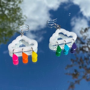 May include: White cloud shaped earrings with rainbow colored raindrops hanging from the bottom.