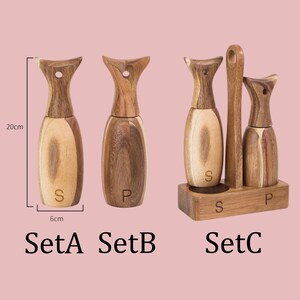 以下が含まれることがあります： ユニークなデザインの木製ソルト＆ペッパーシェーカー。シェーカーの高さは約20cm、幅6cmです。セットには、個別のシェーカーとホルダー付きのセットが含まれています。「S」と「P」の文字が見えます。