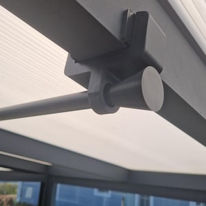 Op de afbeelding: Een zwarte metalen beugel bevestigd aan een grijs plafond met een zwarte metalen stang die er vanaf steekt. De beugel heeft een ronde, zwarte plastic eindkap.