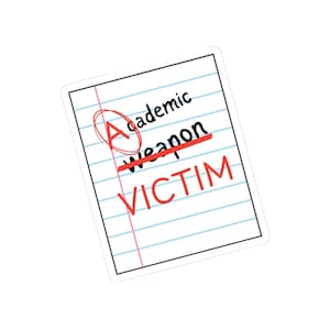 May include: A sticker featuring a sheet of lined paper with the words "academic weapon" crossed out in red and replaced with "VICTIM". The word "A" is circled in red.