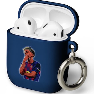 Könnte beinhalten: Eine marineblaue AirPod-Hülle mit einem silbernen Karabinerhaken. Die Hülle hat ein weißes Innere und enthält weiße AirPods. Auf der Vorderseite befindet sich eine farbenfrohe Grafik einer Person in einem Fußballtrikot.