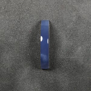 May include: A navy blue bracelet with two white dots. The bracelet is a simple, minimalist design, perfect for everyday wear. The bracelet is made of a smooth, solid material.
