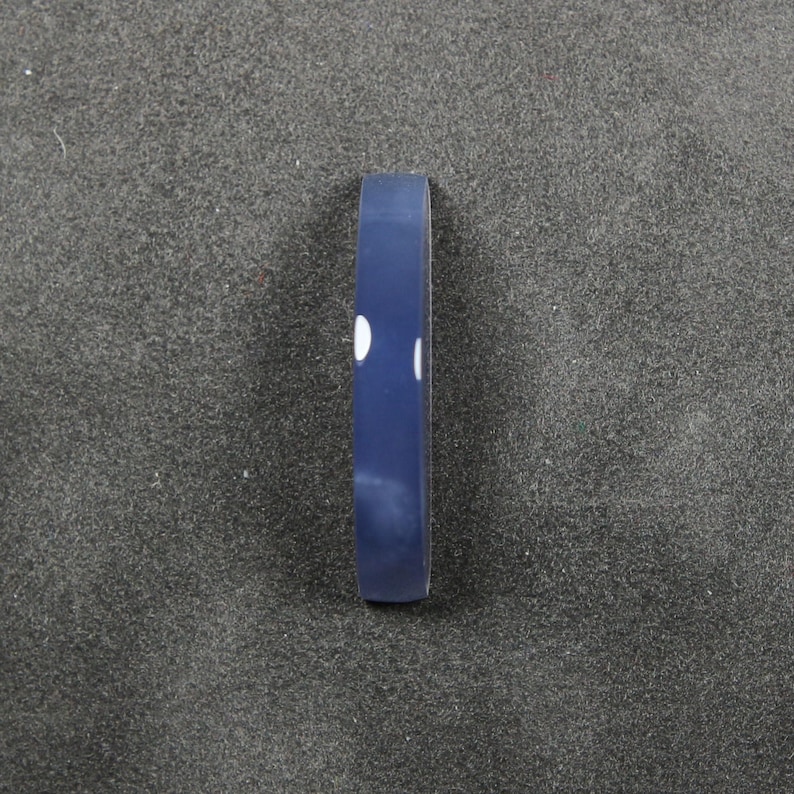 May include: A navy blue bracelet with two white dots. The bracelet is a simple, minimalist design, perfect for everyday wear. The bracelet is made of a smooth, solid material.
