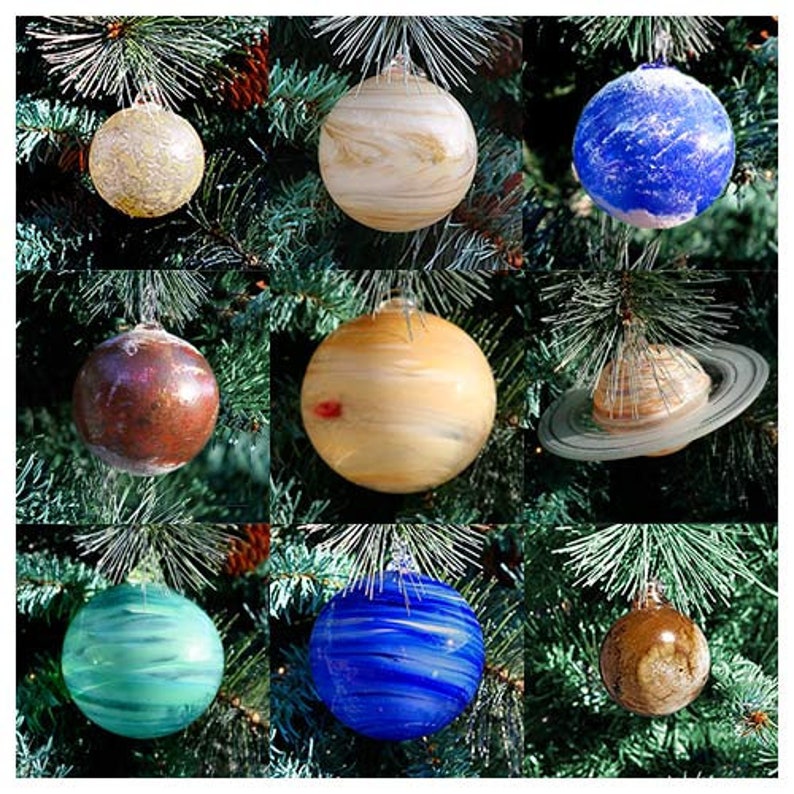 May include: Nine glass ornaments shaped like planets, each with a different color and design. The ornaments are hanging from a Christmas tree.