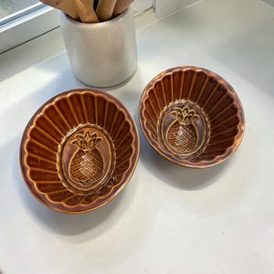 May include: A set of three ceramic mugs with a speckled, matte finish. The mugs are in shades of cream, light gray, and dark gray. Each mug has a simple, minimalist design and a rounded handle.