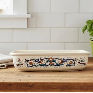 May include: A rectangular off-white ceramic baking dish featuring a decorative horizontal band of intricate floral and scrollwork patterns in shades of deep blue, orange, and green painted along the exterior side of the vessel.