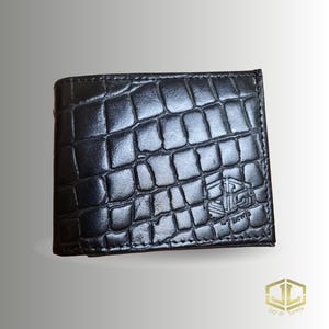 May include: Black leather wallet with a crocodile skin texture. The wallet has a small logo on the lower right corner. The brand name "Jay & Lewis" is printed in gold on the bottom right corner.