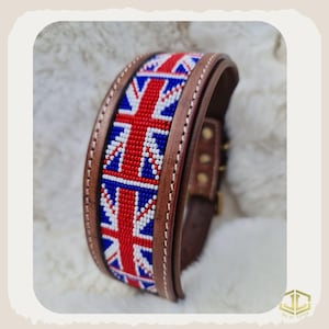Könnte beinhalten: Ein braunes Leder-Halsband für Hunde mit einem Union-Jack-Muster aus roten, weißen und blauen Perlen. Das Halsband hat einen Schnallenverschluss und weiße Nähte. Das Halsband ist etwa 3,8 cm breit.