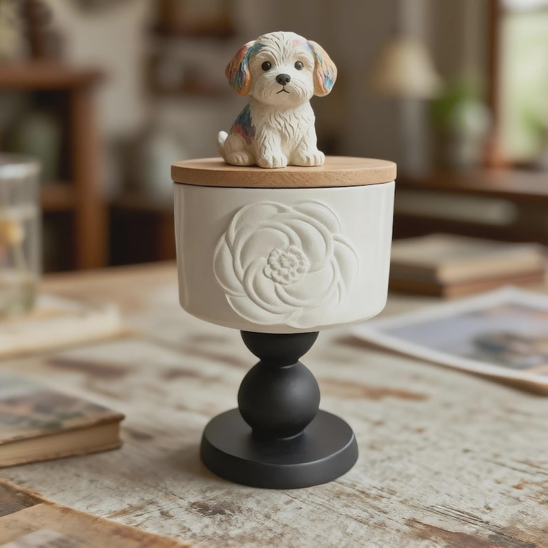 Peut inclure: Un r&eacute;cipient en c&eacute;ramique blanche avec un couvercle en bois et une fleur en relief. Une petite figurine de chien color&eacute;e est pos&eacute;e sur le couvercle. Le r&eacute;cipient est soutenu par un socle noir, cr&eacute;ant un &eacute;l&eacute;ment d&eacute;coratif.