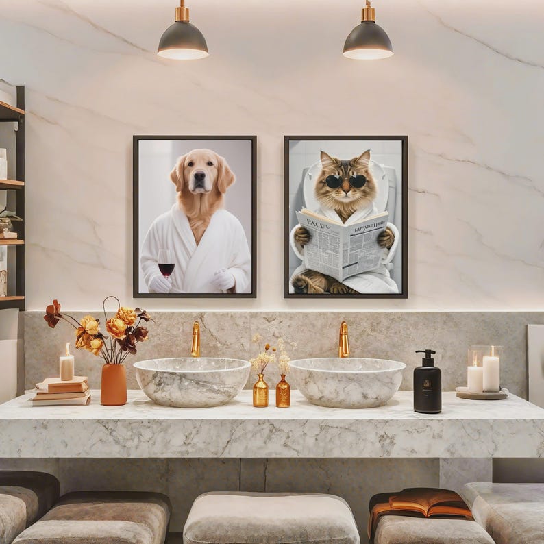May include: Two framed art prints of animals in a bathroom setting. One print features a dog in a white robe holding a glass of wine. The other print shows a cat wearing sunglasses and reading a newspaper. The bathroom has marble sinks and gold fixtures.
