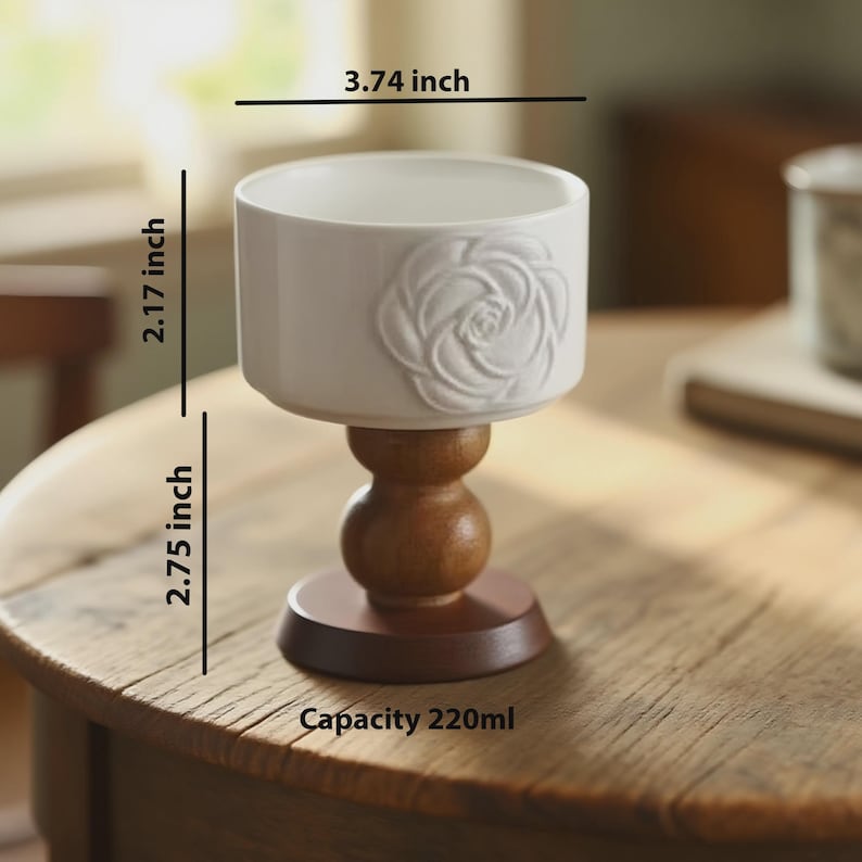 Peut inclure: Une tasse en c&eacute;ramique blanche avec un motif de rose, de 9,5 cm de large, 5,5 cm de haut, et une base en bois de 7 cm de haut. La tasse a une capacit&eacute; de 220 ml. La tasse est sur une table en bois.