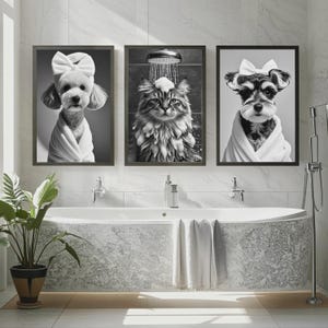 May include: Three framed black and white prints of pets in a bathroom setting. The prints feature a dog with a bow, a cat in the shower, and a dog in a robe. A bathtub, plant, and towels are in the foreground.