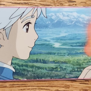 Peut inclure: Un marque-page rectangulaire en papier illustr&eacute; d'un personnage de style anime aux cheveux blancs courts regardant un petit esprit de feu orange brillant flottant au-dessus d'une paume ouverte, devant des collines et des montagnes lointaines.