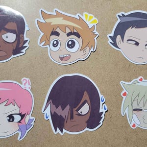 May include: Six cartoon-style stickers featuring various character expressions. The stickers depict faces with different emotions, including surprise, happiness, and anger. The color palette includes shades of brown, pink, and blonde, with white outlines.
