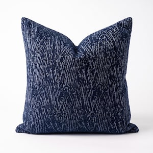 May include: A square throw cushion featuring a deep navy blue and light grey abstract pattern. The design consists of vertical, textured, organic lines that create a repeating, chevron-like effect across the entire surface of the fabric cover.