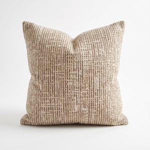 May include: A square decorative pillow with a textured, woven design. The pillow features a neutral color palette of beige and off-white, with a grid-like pattern. The pillow is a soft furnishing for a bed or sofa.