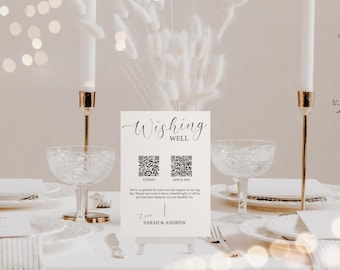 Puede incluir: Una tarjeta blanca con el texto "Wishing Well" en escritura cursiva negra. Dos códigos QR en blanco y negro se muestran debajo del texto, etiquetados como "Venmo" y "Apple Pay". La tarjeta también incluye el texto "We're so grateful for your love and support on our big day. Should you wish to leave a heartfelt gift, it will be just one more thing for us to be thankful for." y "Love, Sarah & Andrew".