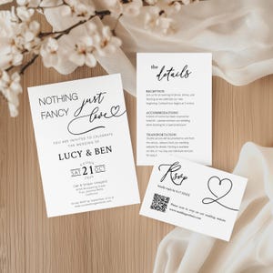 Könnte beinhalten: Ein Set weißer Hochzeitspapeterie mit schwarzem Text. Die Einladung lautet "Nothing Fancy Just Love" und enthält die Namen Lucy & Ben, das Datum und den Veranstaltungsort. Zusätzliche Karten mit Empfangs-, Unterkunfts- und RSVP-Informationen.