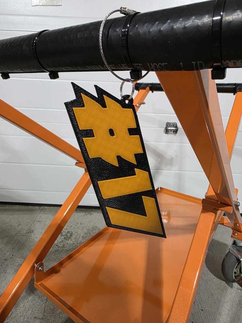 May include: A black and orange metal cart with a black and yellow tag that says "LIZ" hanging from it.