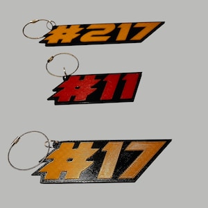 May include: Three black and yellow keychains with a silver chain. The keychains have the numbers #217, #11, and #17 printed on them.