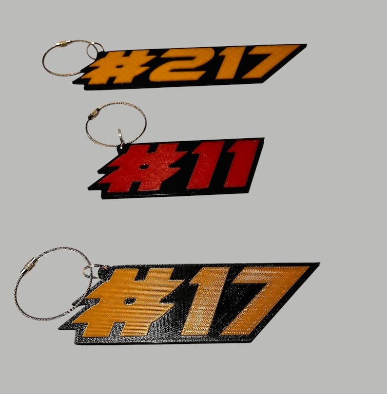 May include: Three black and yellow keychains with a silver chain. The keychains have the numbers #217, #11, and #17 printed on them.