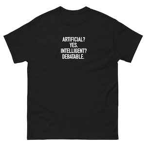 Puede incluir: Camiseta negra con el texto blanco: "ARTIFICIAL? YES. INTELLIGENT? DEBATABLE." La camiseta tiene cuello redondo y mangas cortas.