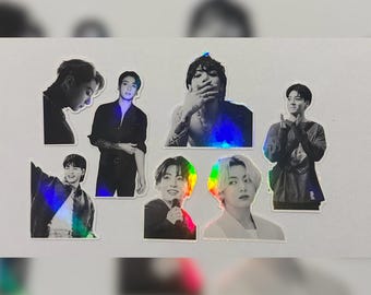 May include: A set of seven black and white holographic stickers featuring different images of a boy band. The stickers are on a white background.