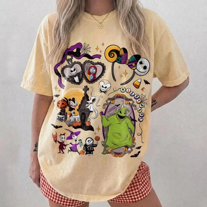 May include: Pale yellow t-shirt with a vibrant graphic design showcasing characters and imagery from "The Nightmare Before Christmas." The design includes Jack Skellington, Sally, Zero, Oogie Boogie, and other iconic elements. The shirt has a round neck and short sleeves.