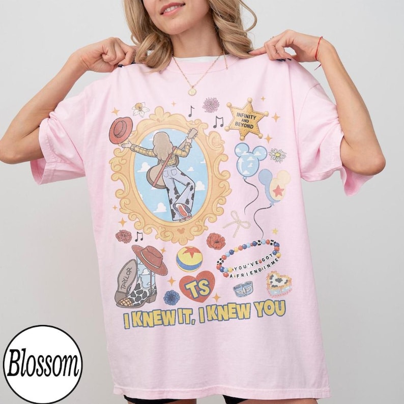 May include: A light pink t-shirt featuring a graphic print of a person with a guitar inside an ornate gold frame, a star with the text INFINITY AND BEYOND, balloons, a beaded bracelet with the text YOU'VE GOT A FRIEND IN ME, and the text I KNEW IT, I KNEW YOU.