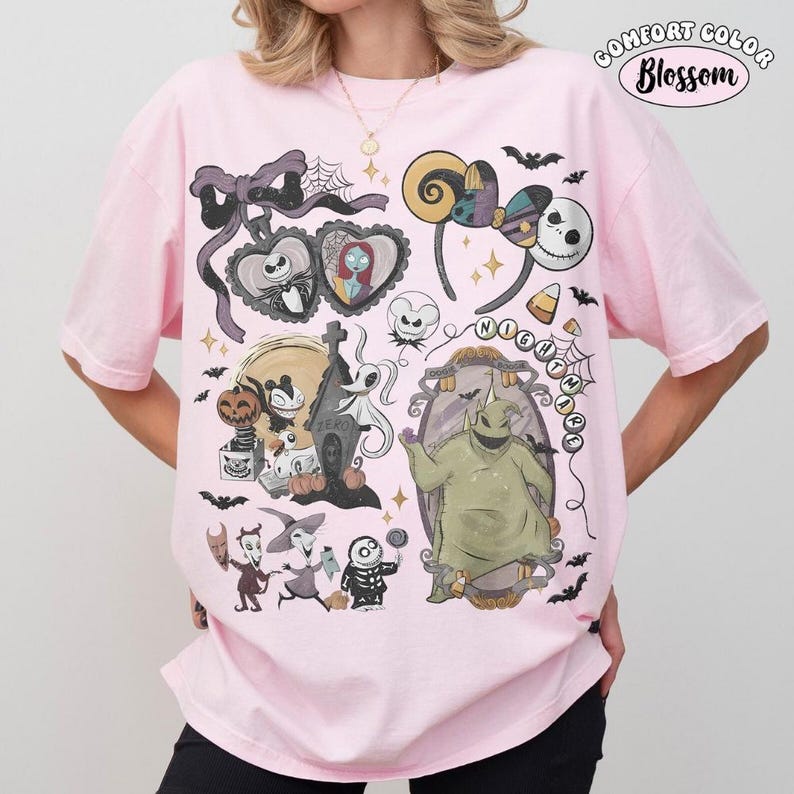 Op de afbeelding: Een lichtroze t-shirt met een grafische print van personages uit The Nightmare Before Christmas, waaronder Jack Skellington, Sally, Zero en Oogie Boogie, samen met een strik, spinnenwebben en de tekst Comfort Color Blossom.