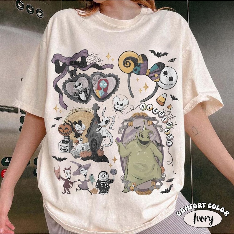 Op de afbeelding: Een ivoorkleurig t-shirt met een grafische print van personages en symbolen uit The Nightmare Before Christmas, waaronder Jack Skellington, Sally, Oogie Boogie, Zero en diverse Halloween-thema iconen zoals vleermuizen, pompoenen en spinnenwebben.