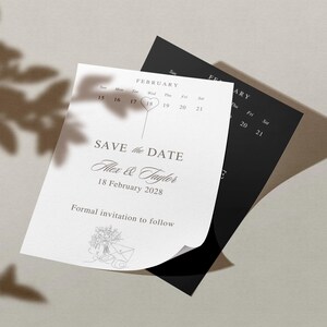 以下が含まれることがあります： 結婚式の招待状の束。一番上のカードは白で、「Save the Date」の文字と「Alex & Taylor」の名前、日付「2028年2月18日」が書かれています。その背後には黒いカードがあります。背景には葉の影があります。