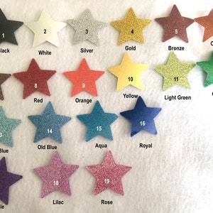 Op de afbeelding: Een kaart met 19 verschillende glitterkleuren, elke kleur wordt weergegeven door een stervorm. De kleuren zijn zwart, wit, zilver, goud, brons, koper, bruin, rood, oranje, geel, lichtgroen, groen, lichtblauw, oudblauw, aqua, koninklijkblauw, paars, lila en roze.