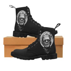 K&ouml;nnte beinhalten: Schwarze Canvas-Stiefel mit einem grafischen Aufdruck von Frankensteins Monster an der Seite. Die Stiefel haben einen Schn&uuml;rverschluss und eine dicke Sohle.