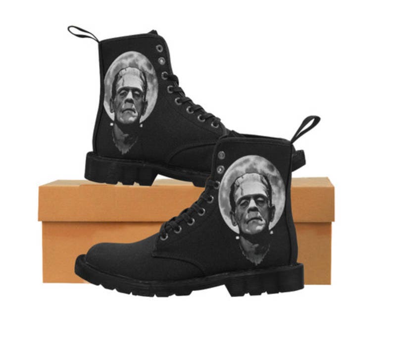 K&ouml;nnte beinhalten: Schwarze Canvas-Stiefel mit einem grafischen Aufdruck von Frankensteins Monster an der Seite. Die Stiefel haben einen Schn&uuml;rverschluss und eine dicke Sohle.