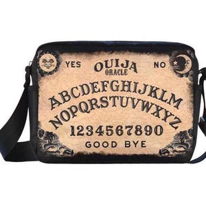 Può includere: Una borsa a tracolla in tela nera con un design vintage di una tavola Ouija. La borsa presenta le lettere dell'alfabeto, i numeri da 0 a 9 e le parole "YES", "NO", "GOOD BYE" e "OUIJA ORACLE".