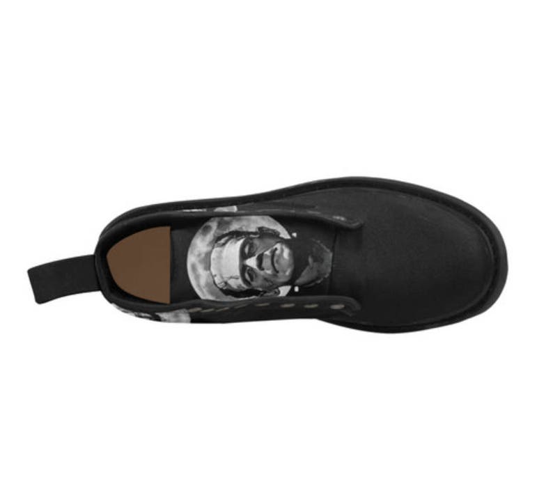 K&ouml;nnte beinhalten: Schwarze Lederstiefel mit einem grafischen Aufdruck eines Gesichts auf der Seite. Das Gesicht ist in Schwarzwei&szlig; gehalten und scheint ein Monster zu sein.