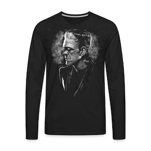 Może przedstawiać: Czarny t-shirt z długim rękawem z białym nadrukiem Frankensteina. Potwór patrzy w bok z poważnym wyrazem twarzy.