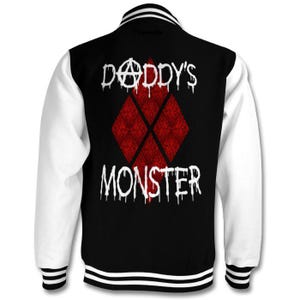 May include: Black and white varsity jacket with red diamond pattern and the text "Daddy's Monster" in white dripping paint letters.